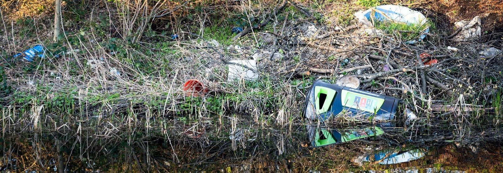 Polluted waterway - litter contaminating a riverbank